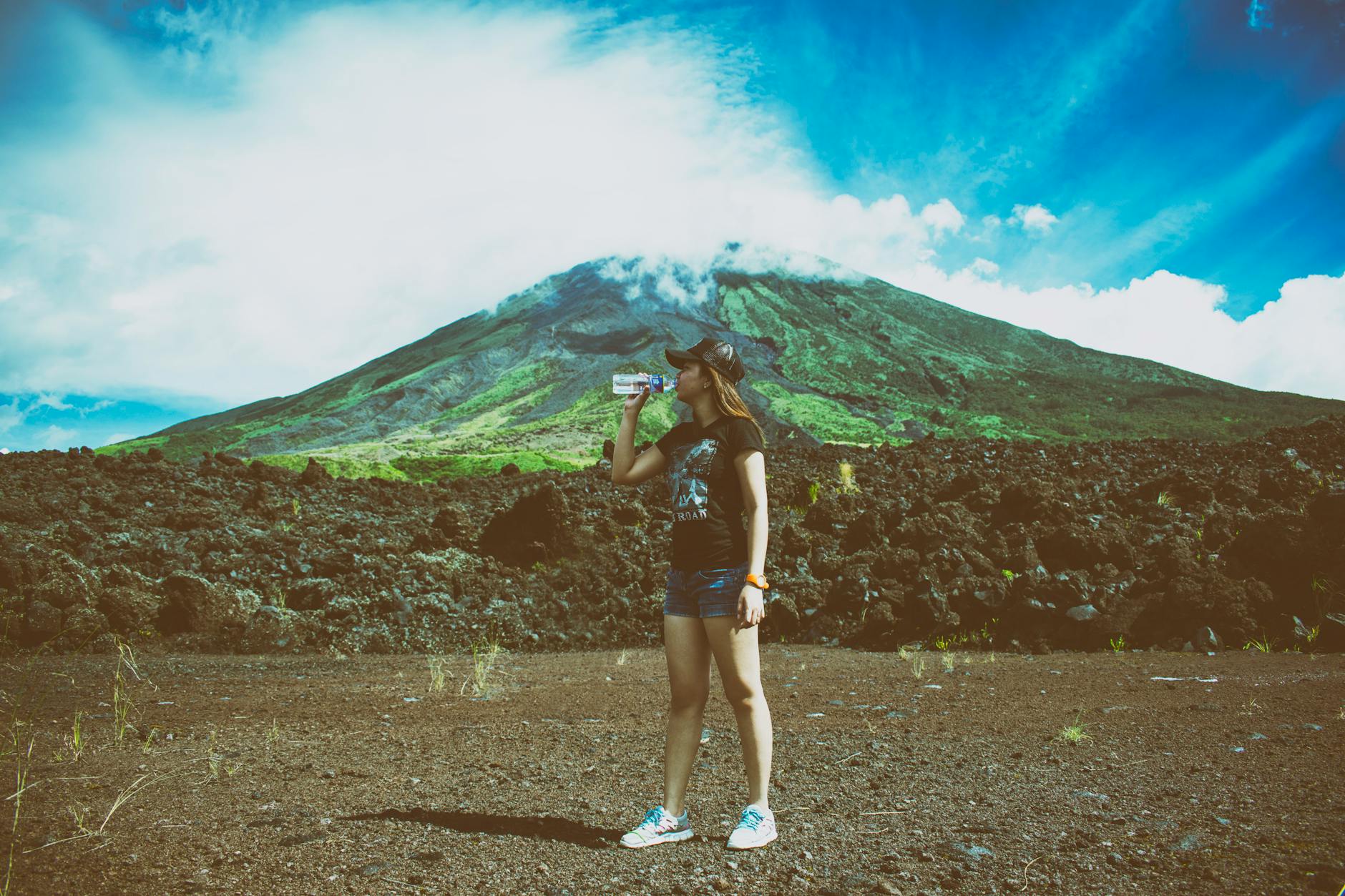 woman drinking water beside mountain